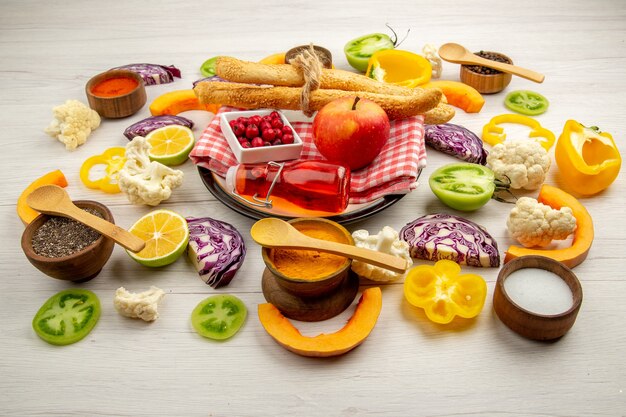 Vue de dessous légumes hachés pain aux pommes bouteille rouge sur serviette sur plateau blanc diverses épices dans de petits bols sur table