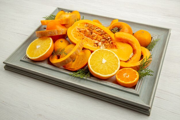 Vue de dessous moitié courge musquée coupée orange kaki mandarines sur cadre sur tableau blanc