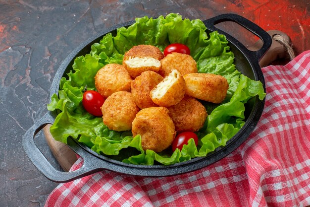 Vue de dessous nuggets de poulet laitue tomates cerises dans une casserole sur fond rouge foncé