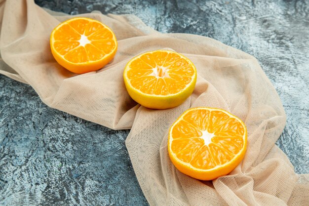 Vue de dessous des oranges coupées sur un châle beige sur une surface sombre