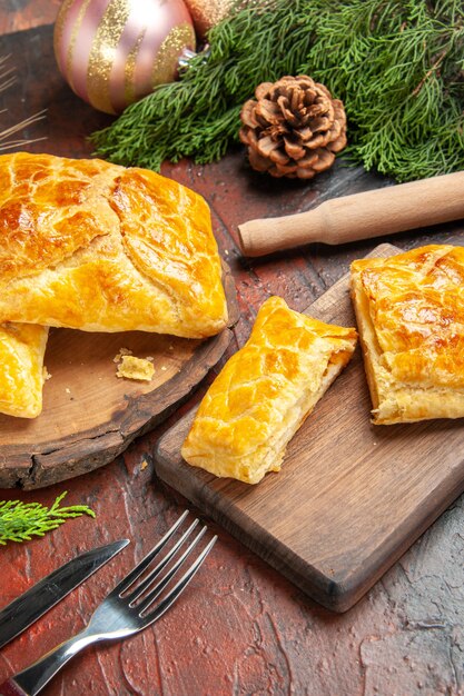 Vue de dessous penovani khachapuri sur des branches et des cônes de pin à rouleau à pâtisserie sur une table rouge foncé