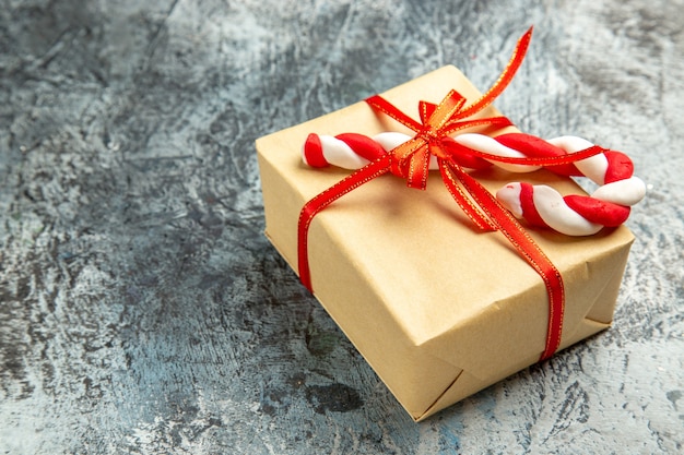 Vue de dessous petit cadeau attaché avec des bonbons de Noël ruban rouge sur gris