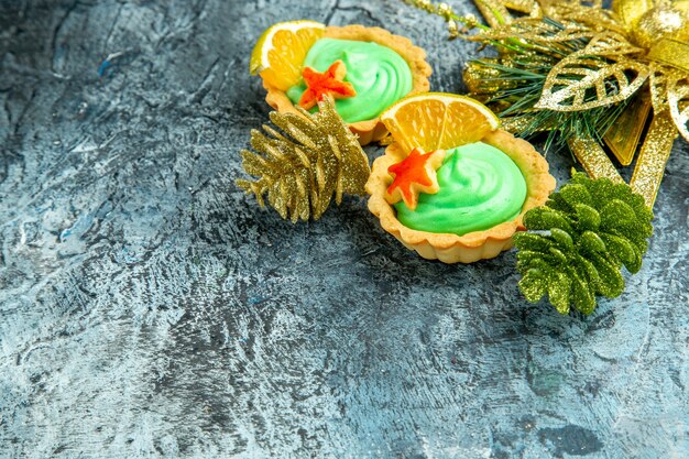 Vue de dessous de petites tartes avec des ornements de Noël à la crème pâtissière verte sur une surface grise avec espace de copie