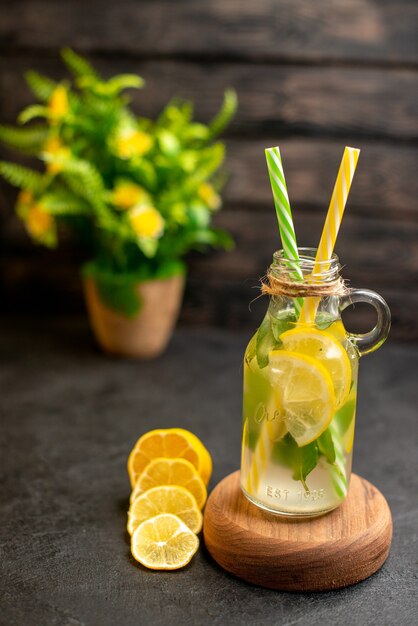 Vue de dessous pipettes jaunes et vertes de limonade sur planche de bois plante en pot de citrons coupés sur une surface en bois