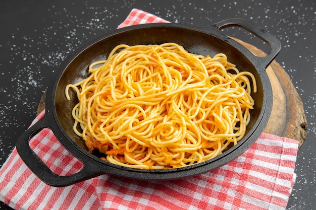 Vue de dessous poêle à spaghetti sur planche de bois sur fond noir