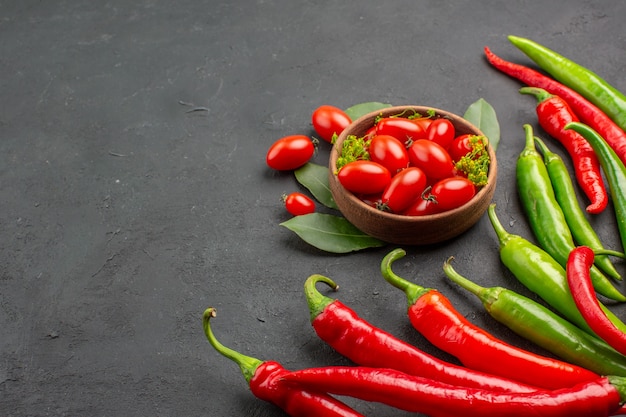 Vue de dessous les poivrons rouges et verts et un bol de tomates cerises sur le côté droit du fond noir