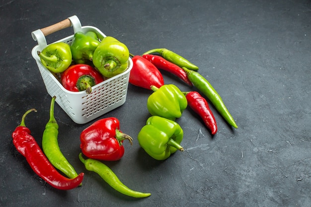 Vue de dessous poivrons verts et rouges dans un panier en plastique piments forts sur fond sombre avec espace libre