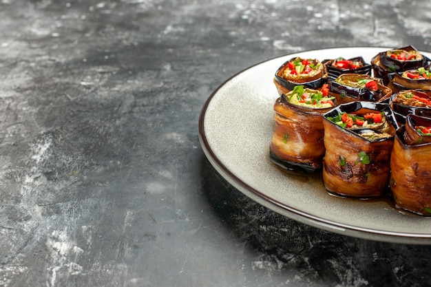 Vue de dessous des rouleaux d'aubergines farcies sur une plaque blanche sur un espace libre gris