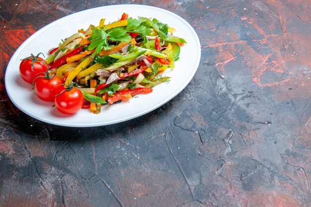 Vue de dessous de la salade de légumes sur une assiette ovale sur un espace de copie de surface sombre