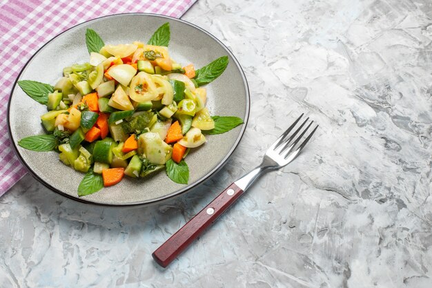 Vue de dessous salade de tomates vertes sur une assiette ovale une fourchette sur une photo de nourriture sombre