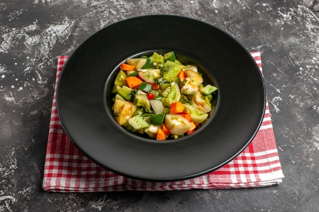 Vue de dessous salade de tomates vertes sur une assiette ovale sur une serviette sombre