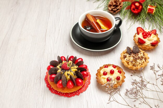 Vue de dessous une tasse de tartes au citron et à la cannelle gâteau aux baies et les feuilles de pin avec des jouets de Noël sur le fond en bois blanc