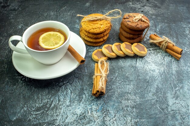 Vue de dessous tasse de thé aromatisée au citron et à la cannelle biscuits biscuits attachés avec des bâtons de cannelle en corde sur un espace libre de table gris