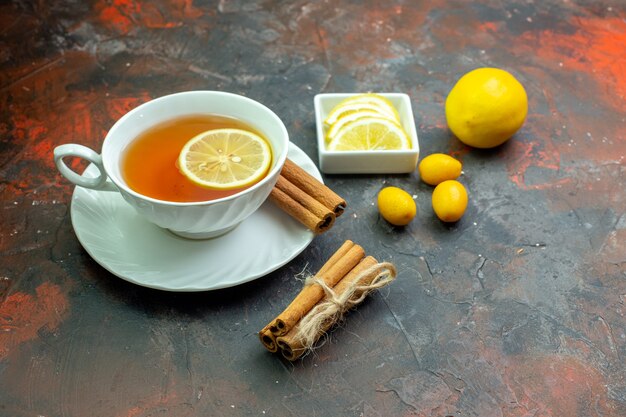 Vue de dessous tasse de thé aromatisée au citron cumcuat tranches de citron dans un petit bol de cannelle sur une table rouge foncé