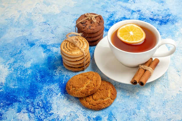 Vue de dessous tasse de thé aromatisée de biscuits au citron et à la cannelle attachés avec une corde sur une table bleue