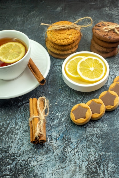 Vue de dessous tasse de thé avec des biscuits au citron et à la cannelle avec des biscuits au chocolat attachés avec des bâtons de cannelle en corde sur une table grise