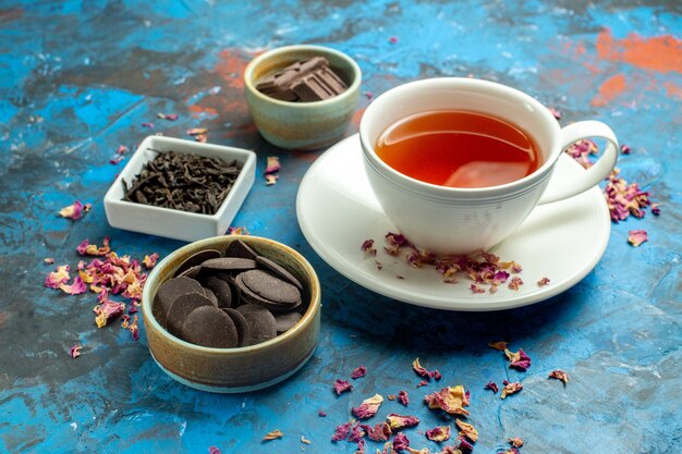 Vue de dessous une tasse de thé chocolats de formes différentes dans de petits bols sur une surface rouge bleu