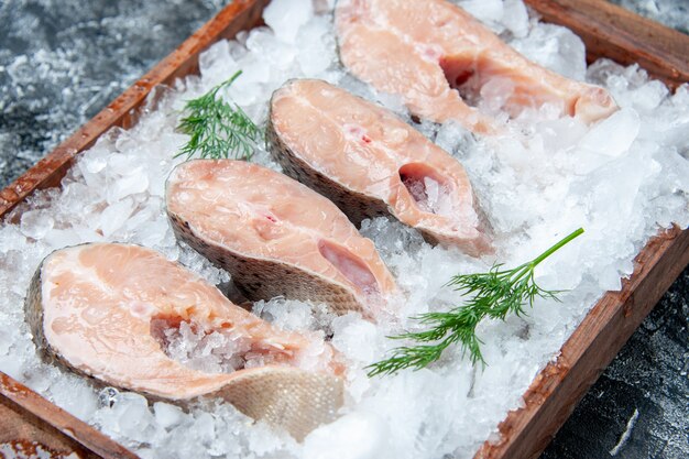 Vue de dessous des tranches de poisson cru avec de la glace sur une planche de bois