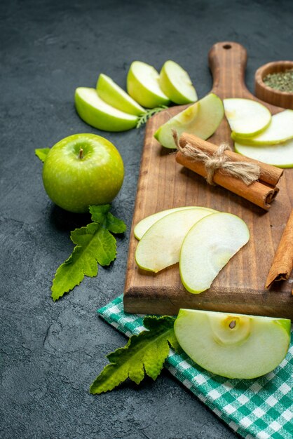 Vue de dessous tranches de pomme et cannelle sur planche à découper poudre de menthe séchée dans un bol nappe vert pomme sur table sombre