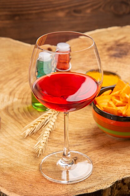 Vue de dessous verre à vin ballon chips de bouteille rouges et vertes dans un bol sur une surface brune