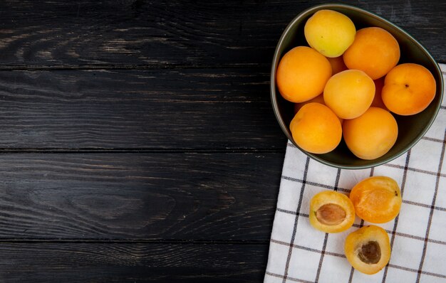 Vue de dessus d'abricots coupés et entiers sur tissu et fond en bois avec espace copie