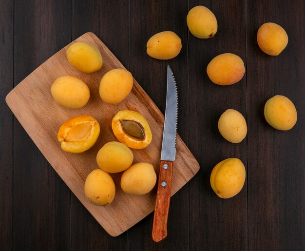 Vue de dessus des abricots avec un couteau sur une planche sur une surface en bois