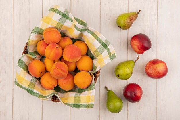 Vue de dessus des abricots dans le panier avec des poires sur fond de bois