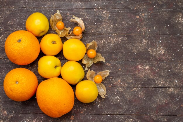 Vue de dessus abricots moelleux doux de couleur orange avec des oranges et physalise de délicieux fruits d'été sur le fond brun gâteau aux fruits