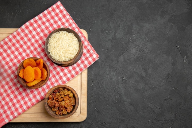 Vue de dessus des abricots secs avec des raisins secs et du riz sur une surface grise aux raisins secs