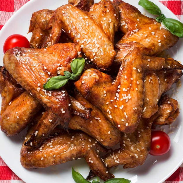 Vue de dessus des ailes de poulet sur plaque avec graines de sésame et tomates cerises