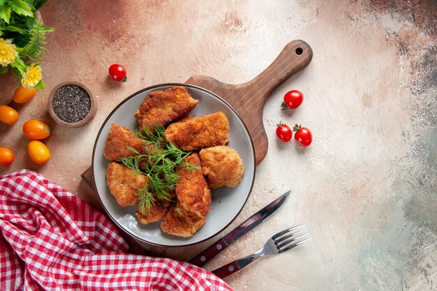 Vue de dessus des ailes de poulet savoureuses avec des verts à l'intérieur de la plaque sur une surface claire