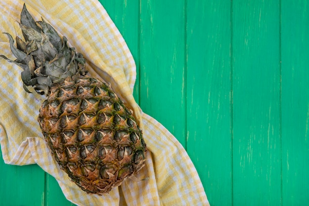 Photo gratuite vue de dessus de l'ananas sur tissu à carreaux et surface verte