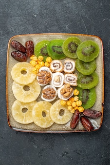 Vue de dessus anneaux d'ananas de fruits secs en tranches et kiwis sur le fond gris raisin sec de fruits secs aigre-douce vitamine santé