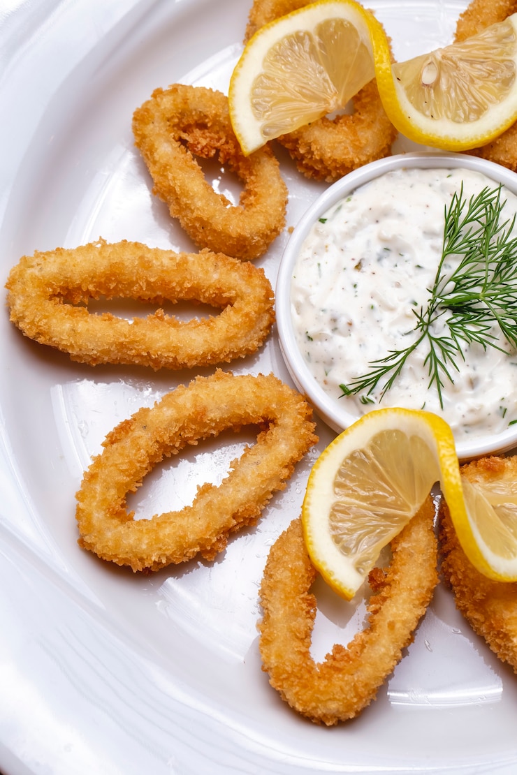 Photo gratuit vue de dessus anneaux de calmar dans la pâte avec sauce et tranches de citron