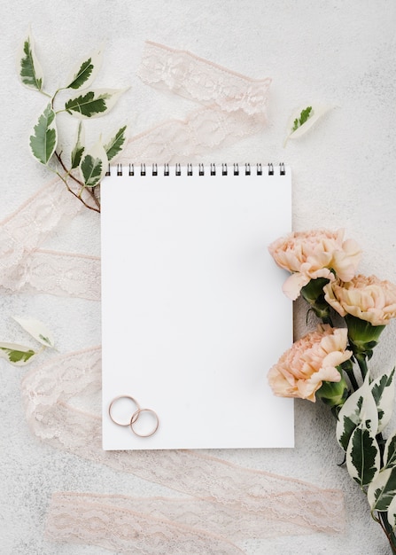 Photo gratuite vue de dessus des anneaux de mariage avec des fleurs sur la table