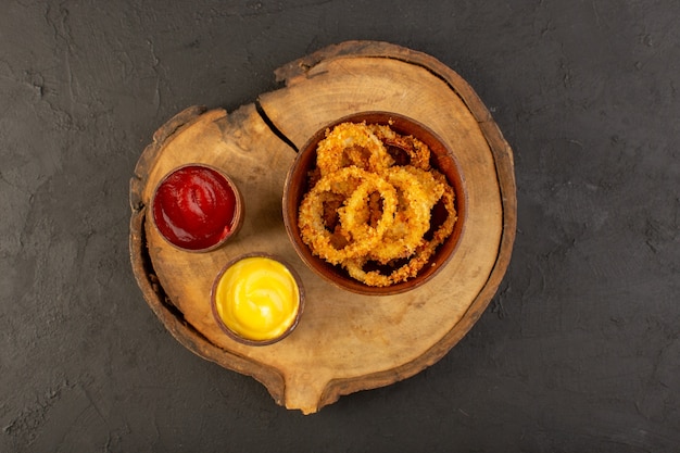 Une vue de dessus des anneaux de poulet frit à l'intérieur de la plaque brune avec du ketchup et de la moutarde