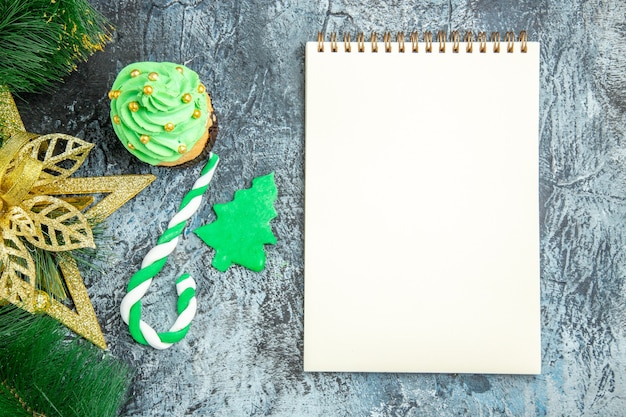 Photo gratuite vue de dessus arbre de noël cupcake noël bonbons noël ornements un cahier sur une surface grise