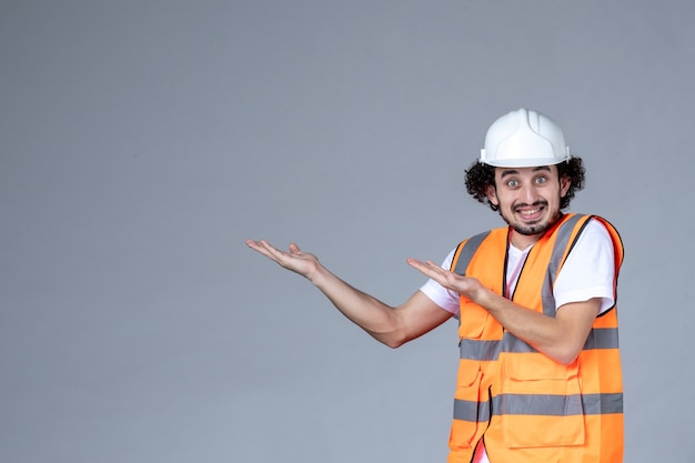 Vue de dessus d'un architecte masculin curieux en gilet d'avertissement avec casque de sécurité et pointant vers le haut sur le côté droit sur le mur de la vague grise