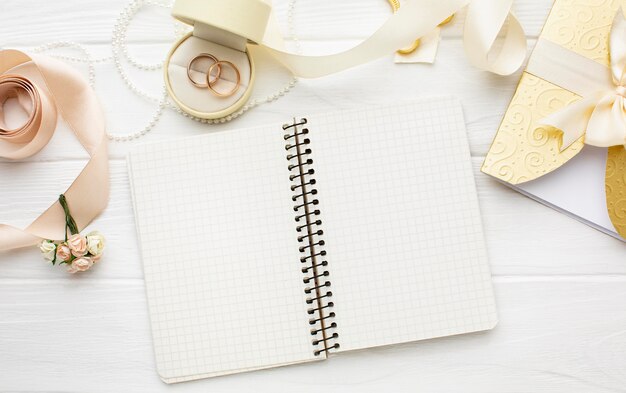 Vue de dessus arrangement de cahier vide et anneaux de mariage