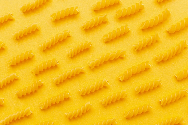 Vue de dessus de l'arrangement de pâtes fusilli sur fond jaune