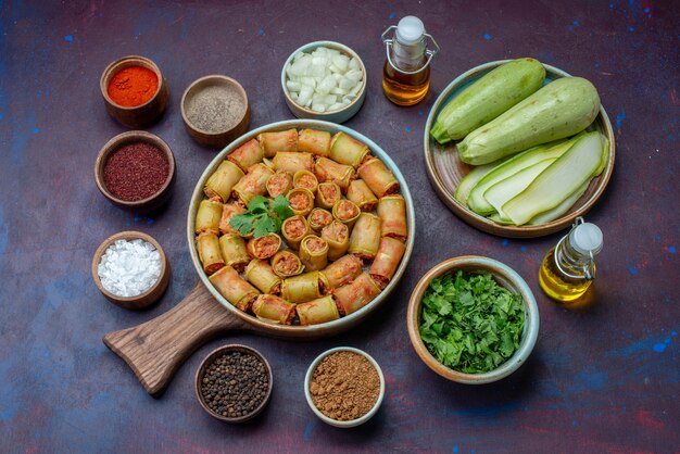 Vue de dessus des assaisonnements à l'intérieur des pots sel poivre avec des rouleaux de viande de courges fraîches sur la surface violet foncé