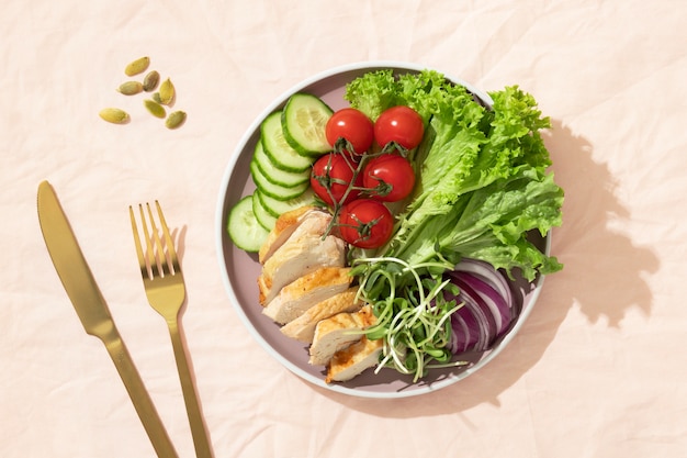 Vue de dessus de l'assiette avec des aliments diététiques céto et une fourchette et un couteau dorés