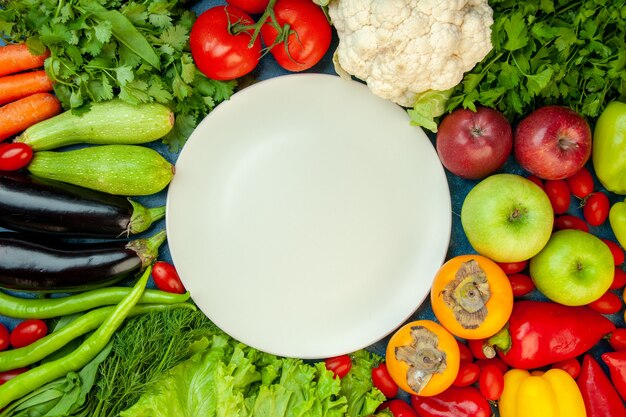 Vue de dessus assiette blanche carotte courgette tomates cerises persil aneth laitue tomates aubergines vert piment kaki pommes