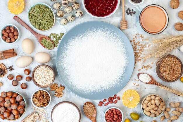 Vue de dessus assiette bleue avec gelée de farine d'oeufs et différentes noix sur un gâteau léger pâte de couleur sucre tarte photo aux noix sucrées