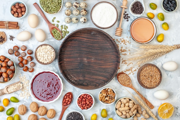 Vue de dessus assiette en bois ronde avec oeufs en gelée différentes noix et graines sur une pâte blanche gâteau au sucre couleur douce biscuit noix photo