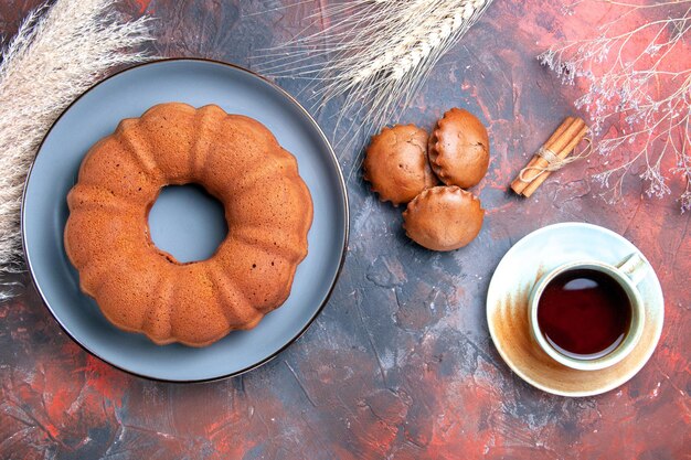 Vue de dessus assiette à gâteaux de cupcakes à gâteaux une tasse de thé bâtons de cannelle et épis de blé