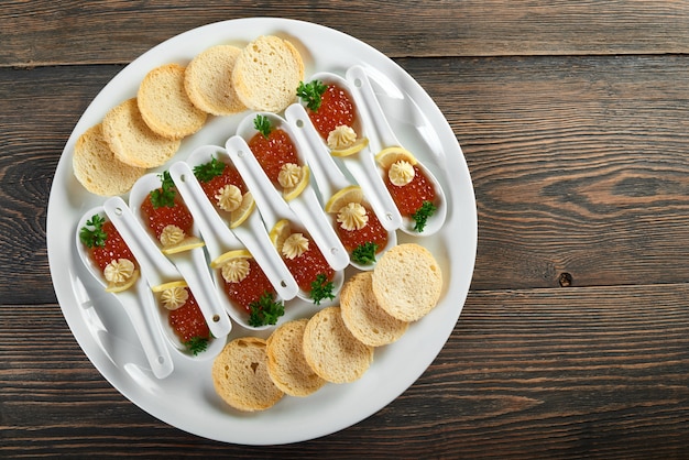 Vue de dessus d'une assiette avec des portions de caviar rouge et des biscottes croustillantes sur la table en bois nutrition alimentaire manger décoration restaurant café cafétéria menu commande luxe concept de mode de vie.