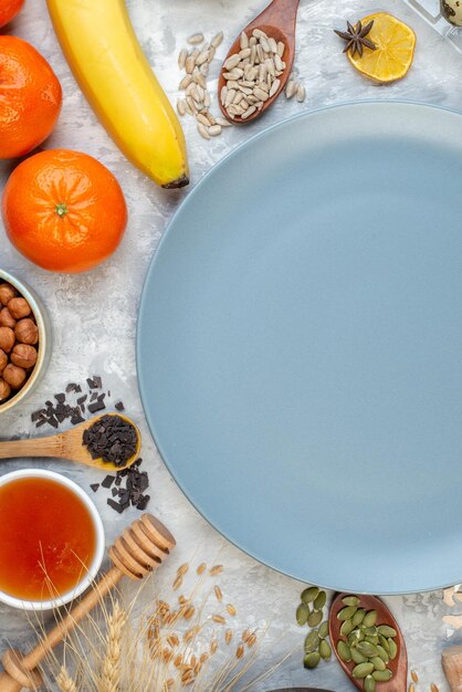 Vue de dessus assiette ronde banane oranges bol de miel bâton de miel sur la table