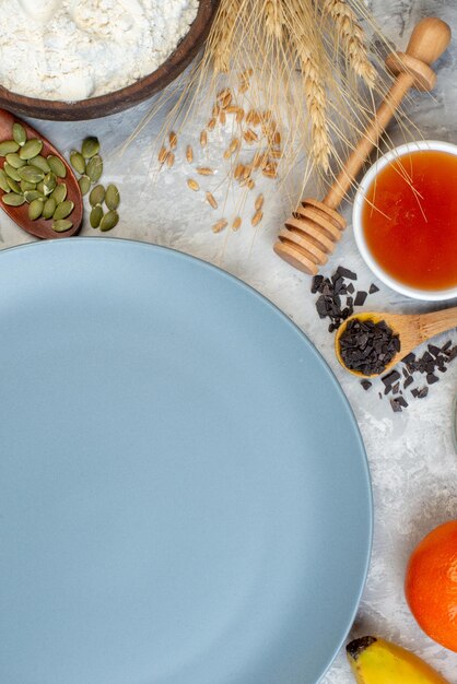 Vue de dessus assiette ronde bol de miel bâton de miel bol de farine sur la table