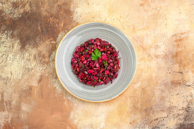 Vue de dessus de l'assiette d'une salade rouge avec des verts dessus sur un backgorund en bois